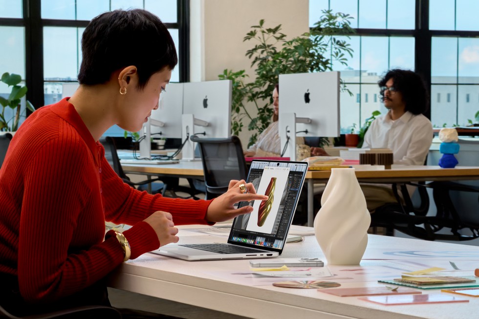 Person at an office desk touching the screen of the new MacBook Pro with PROLED XDR Display