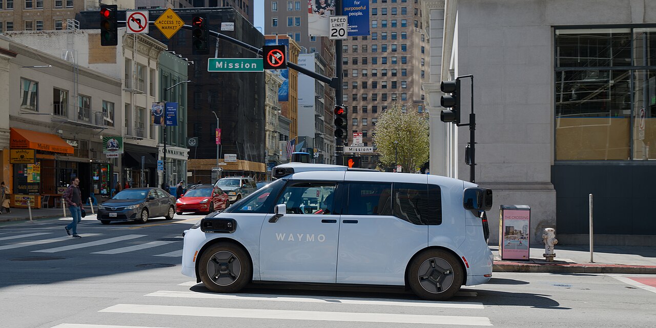 A Waymo Ojai minivan robotaxi driving on a city street
